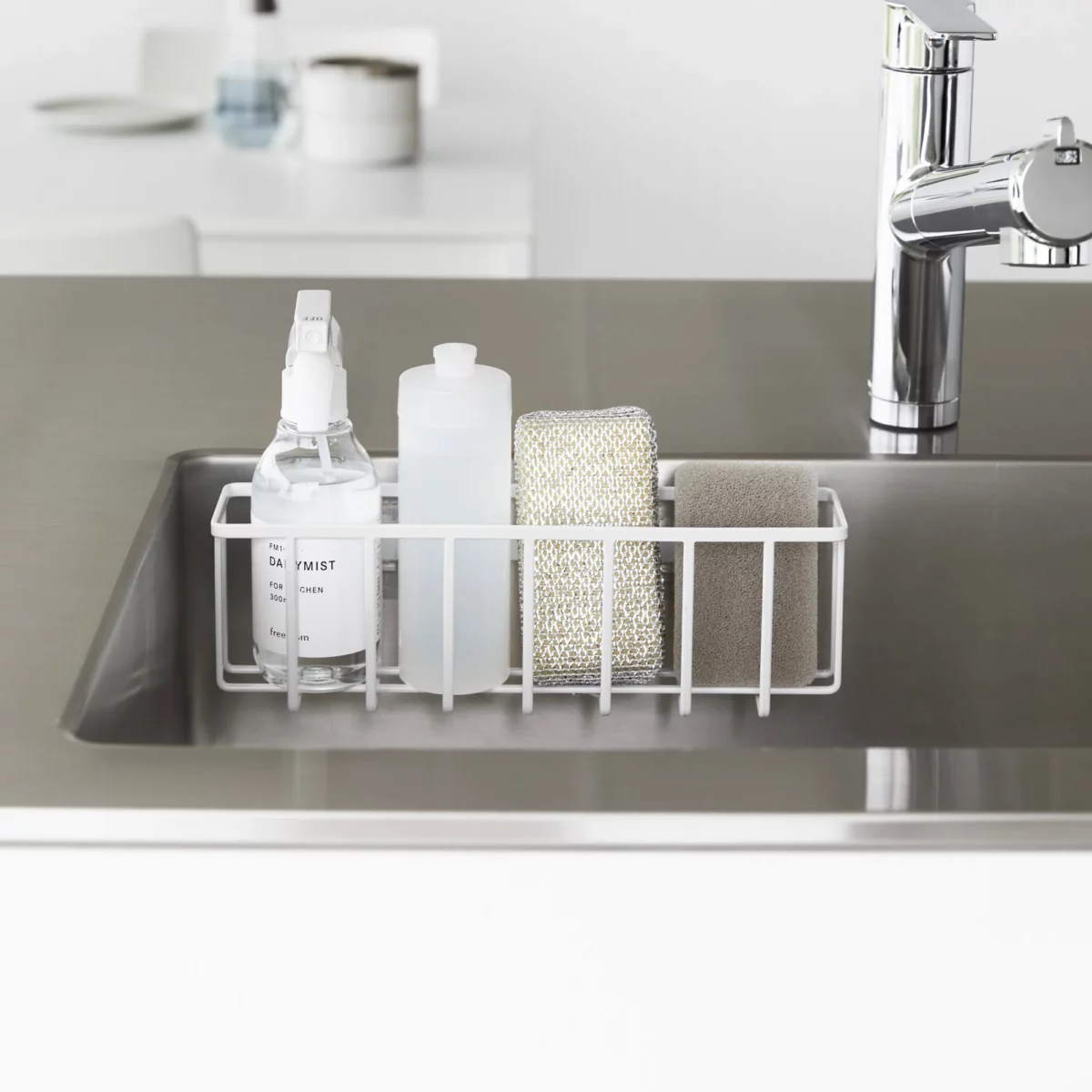 Yamazaki TOWER Film Hook multi-use basket L in white, front view in the sink with bottles and a sponge