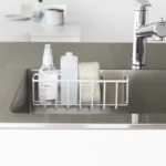Yamazaki TOWER Film Hook multi-use basket L in white, front view in the sink with bottles and a sponge