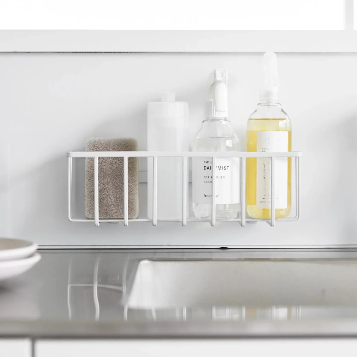 Yamazaki TOWER Film Hook multi-use basket L in white, front view on the wall with bottles and a brush