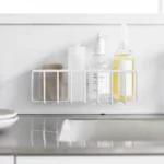 Yamazaki TOWER Film Hook multi-use basket L in white, front view on the wall with bottles and a brush