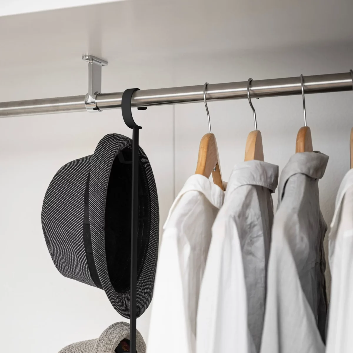 Yamazaki SMART 2-Tier Extendable Clothes Rod in Black; the hat hangs on the hook on the side next to the shirts