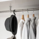 Yamazaki SMART 2-Tier Extendable Clothes Rod in Black; the hat hangs on the hook on the side next to the shirts