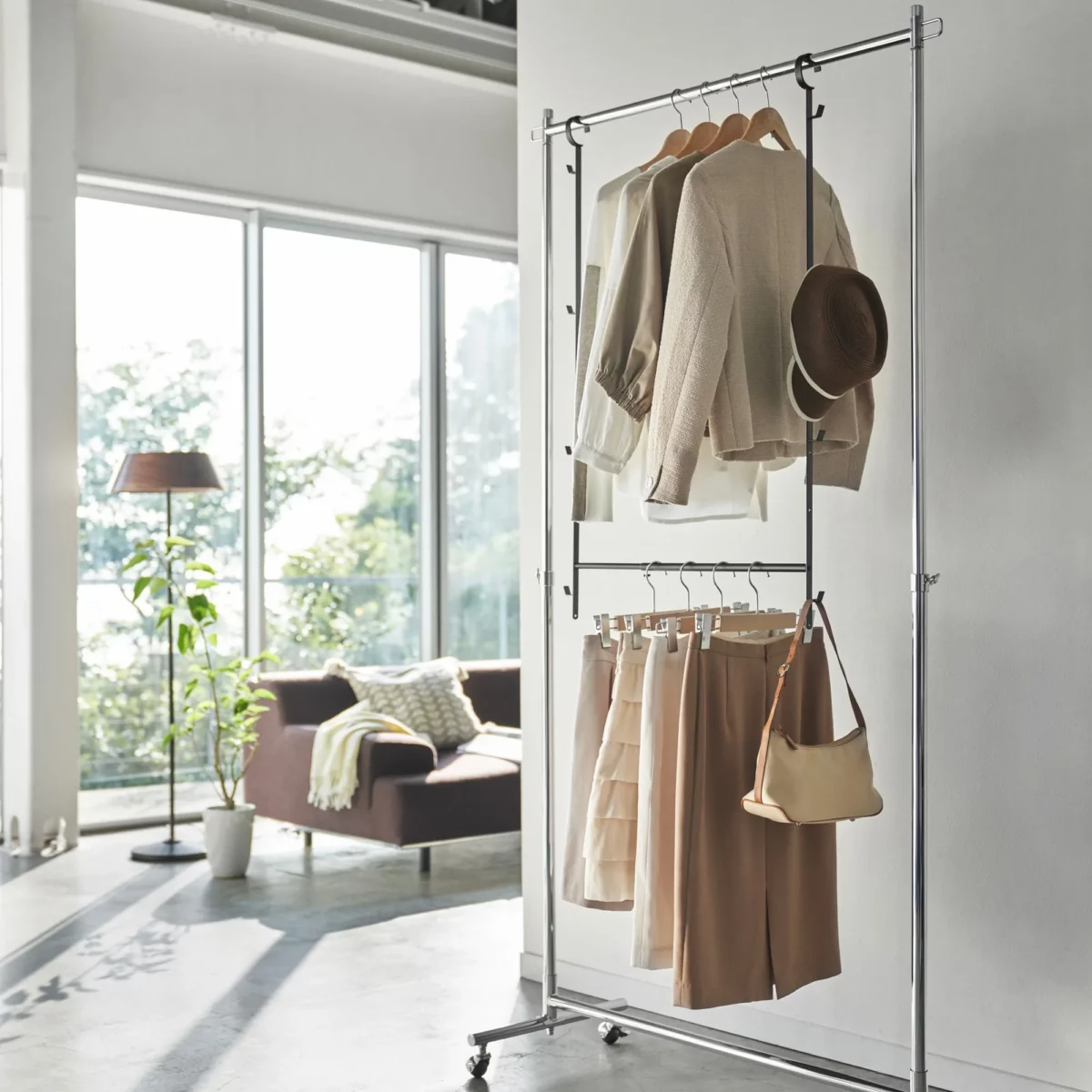 Yamazaki SMART 2-tier extendable clothes rod in black, hung on an open clothes rack in the living room