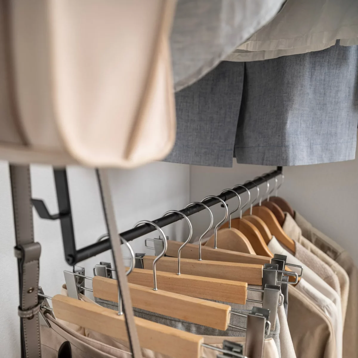 Yamazaki SMART 2-Tier Extendable Clothes Rod in Black, with trouser hangers and a bag strap on the lower rod