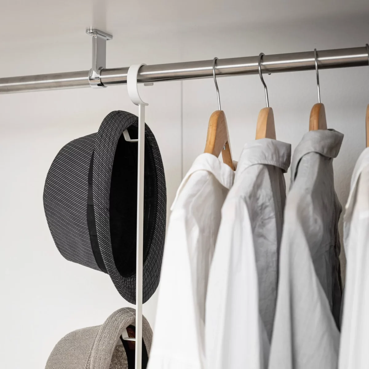 Yamazaki SMART 2-tier extendable clothes rod in white; a hat hangs on the side hook next to the shirts