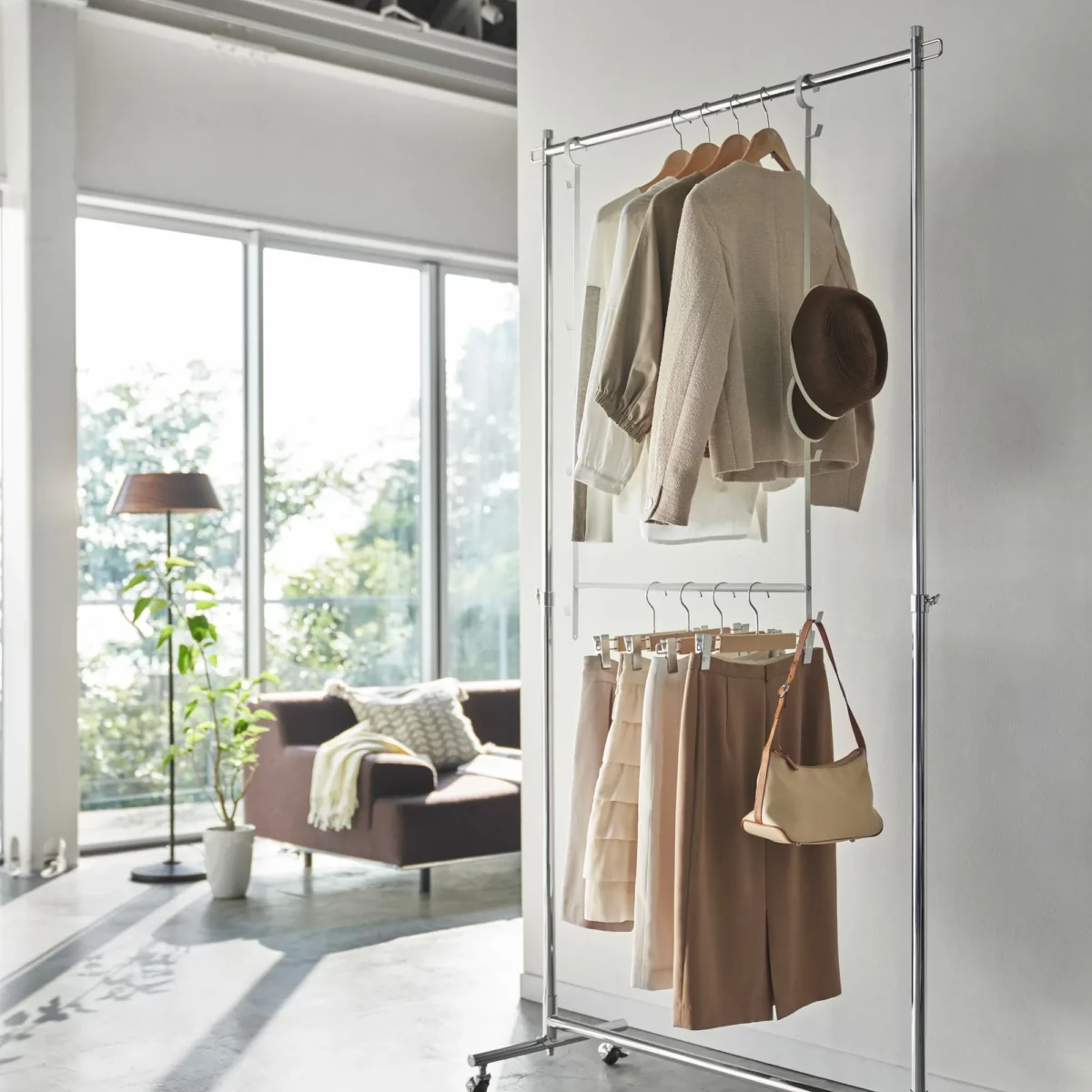 Yamazaki SMART 2-tier extendable clothes rod in white, hung on an open clothes rack in the living room