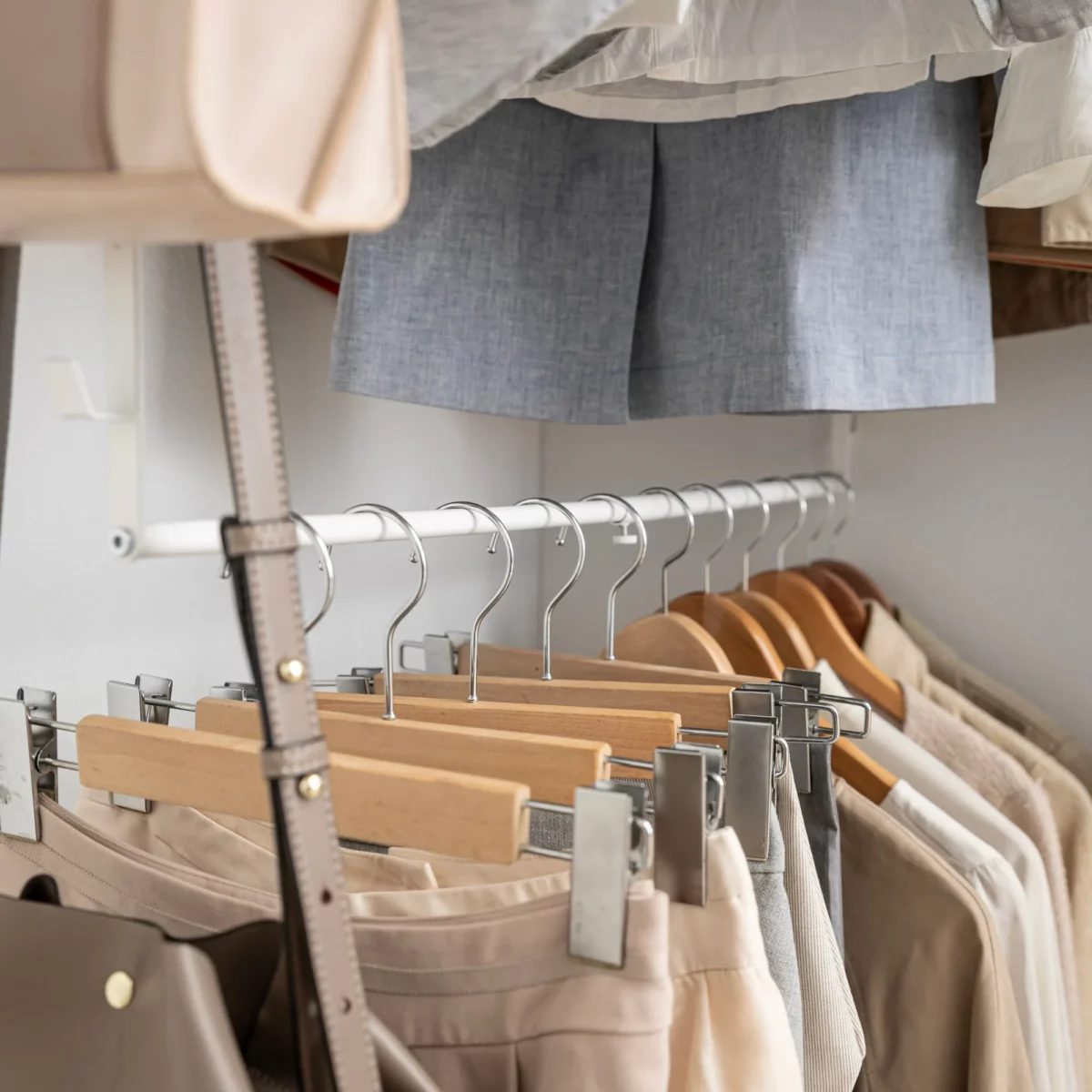 Yamazaki SMART 2-Tier Extendable Clothes Rod in White, with trouser hangers and a bag strap on the lower rod
