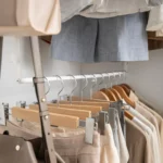 Yamazaki SMART 2-Tier Extendable Clothes Rod in White, with trouser hangers and a bag strap on the lower rod