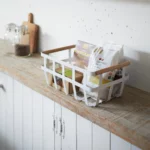 Yamazaki Korb TOSCA gross in Weiss, auf der Holzablage in der Küche, gefüllt mit Snacks und Paketen