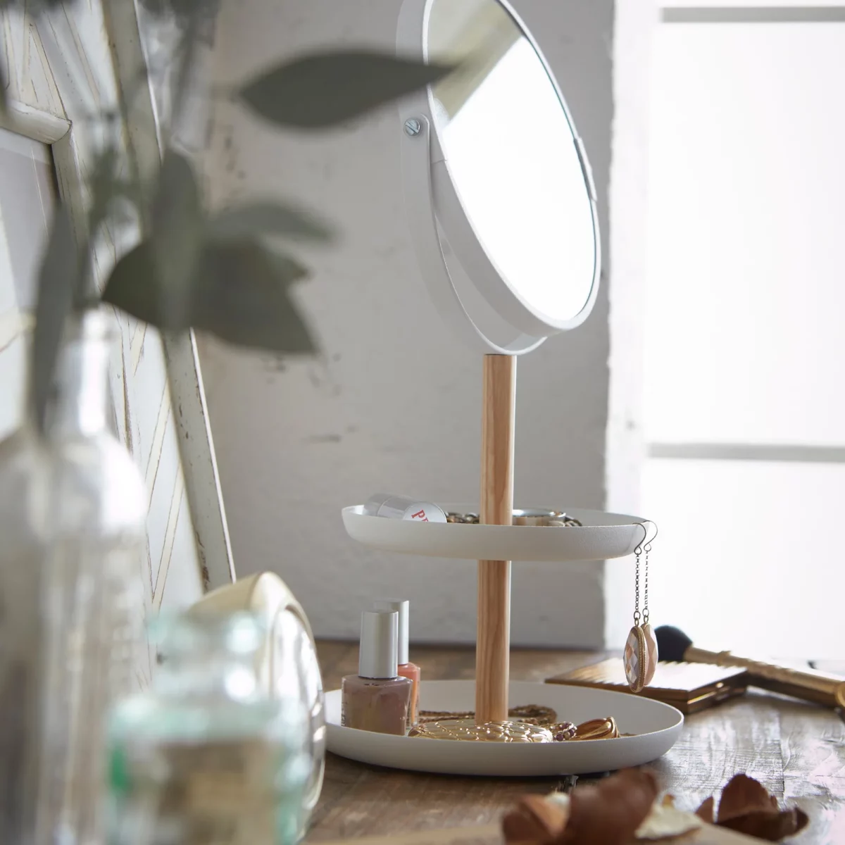 Yamazaki TOSCA Makeup Mirror with Shelves in White, Angled Shot with a Plant in the Foreground and Nail Polish