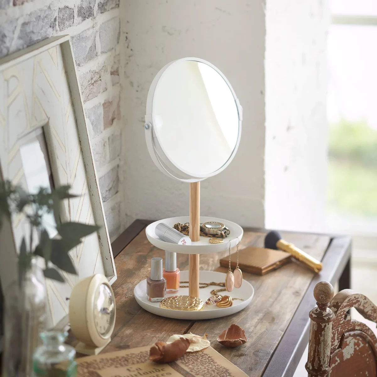 Yamazaki TOSCA makeup mirror with shelves in white, on the vanity next to the makeup brushes and alarm clock