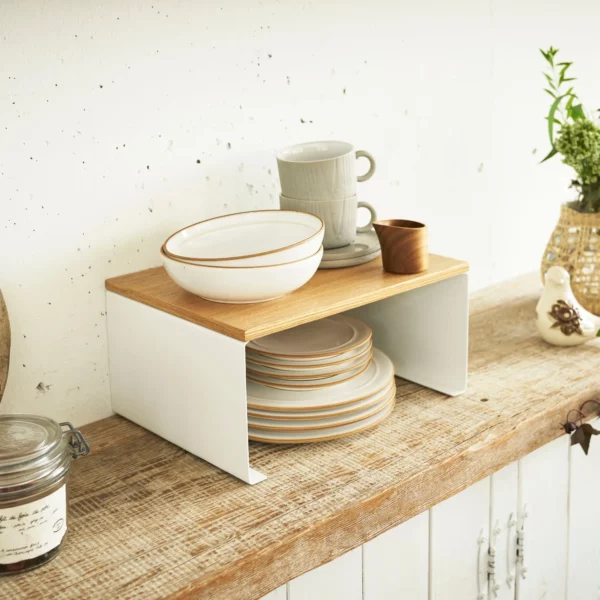 Étagère de cuisine Yamazaki TOSCA empilable, de couleur blanche, avec des bols sur la tablette en bois en haut et des assiettes en dessous