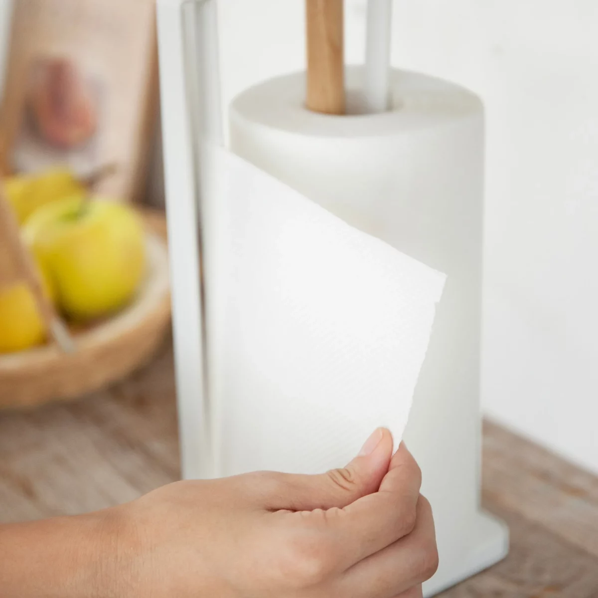 Yamazaki Küchenrollenhalter TOSCA in Weiss, Hand zieht ein Blatt Küchenpapier am Bügel vorbei