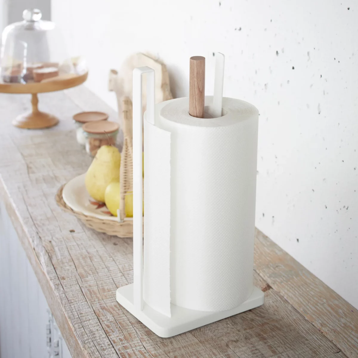 Yamazaki Küchenrollenhalter TOSCA in Weiss, auf einer Holzablage neben Birnen und Gewürzen