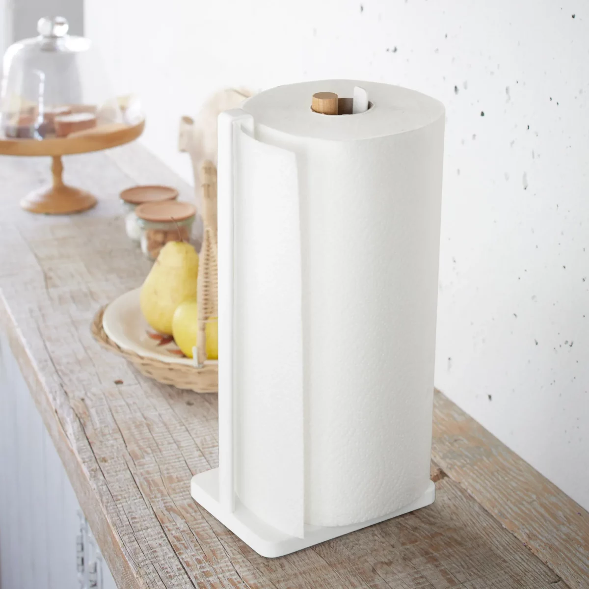 Yamazaki Küchenrollenhalter TOSCA in Weiss, schräg von vorne auf der Holzablage mit voller Rolle