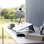 Support 2 en 1 TOWER pour ordinateur et tablette Yamazaki coloris noir, en biais avec un ordinateur fermé sur la table