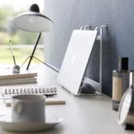 Support 2 en 1 TOWER pour ordinateur et tablette Yamazaki coloris blanc, debout contre le mur avec ordinateur rangé verticalement