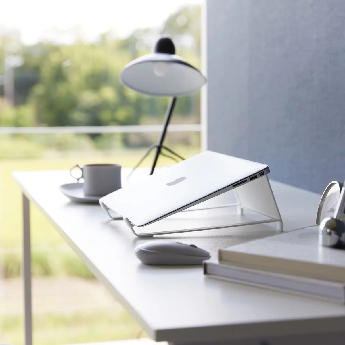 Support 2 en 1 TOWER pour ordinateur et tablette Yamazaki coloris blanc, en biais avec un ordinateur fermé sur la table