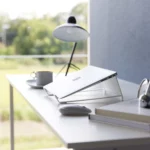 Support 2 en 1 TOWER pour ordinateur et tablette Yamazaki coloris blanc, en biais avec un ordinateur fermé sur la table