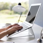 Support 2 en 1 TOWER pour ordinateur et tablette Yamazaki coloris blanc, des mains tapent sur l’ordinateur posé sur le support
