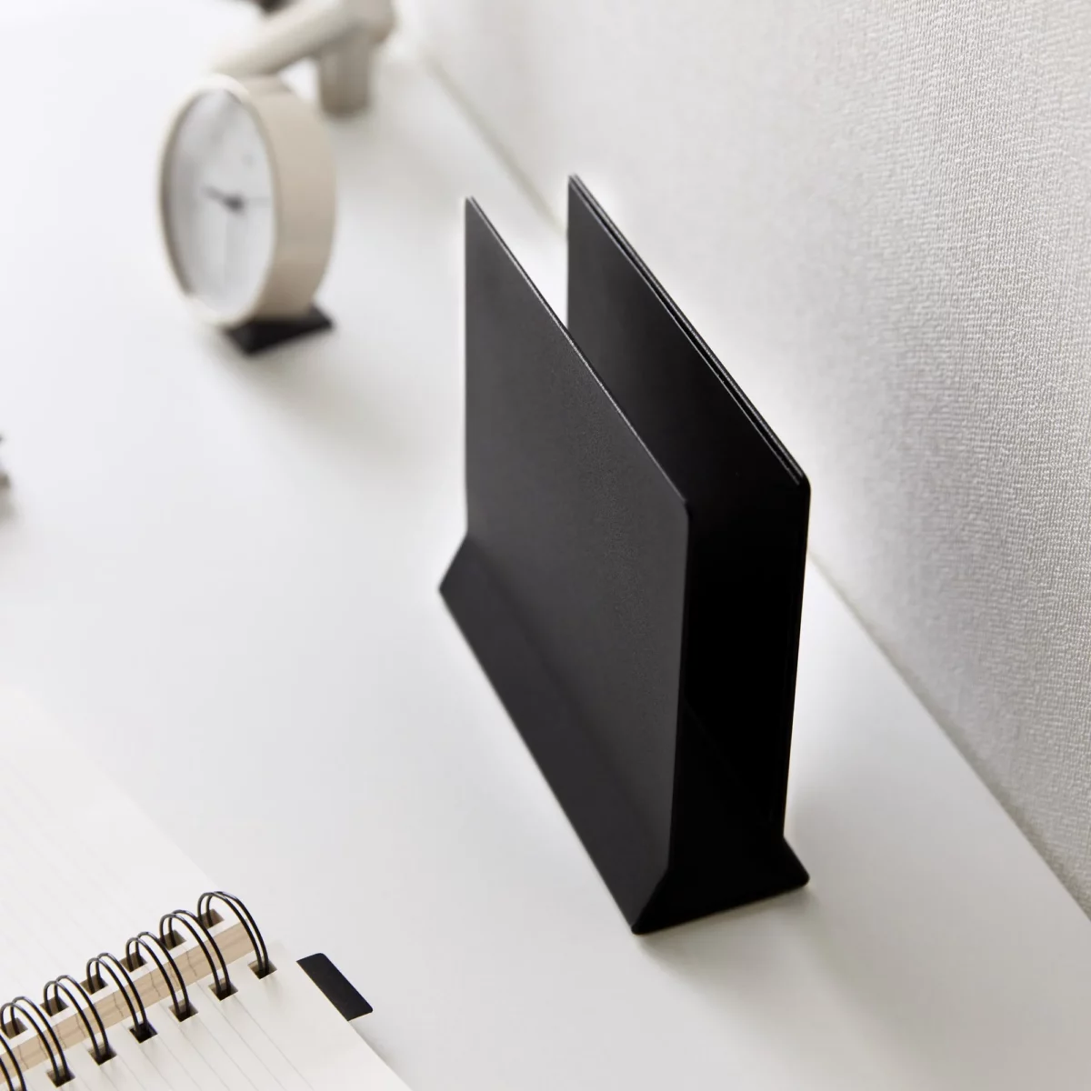 Support pour ordinateur portable Yamazaki TOWER vertical, noir, posé à vide sur le bureau à côté du cahier