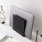 Support pour ordinateur portable Yamazaki TOWER vertical, noir, en position inclinée avec un ordinateur portable devant un mur blanc, en gros plan