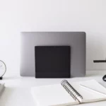 Support pour ordinateur portable Yamazaki TOWER vertical, noir, vu de face sur le bureau avec un bloc-notes