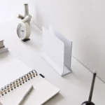 Support pour ordinateur portable Yamazaki TOWER vertical, blanc, posé à vide sur le bureau à côté du cahier