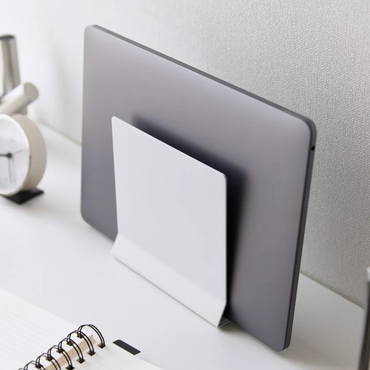 Support pour ordinateur portable Yamazaki TOWER vertical, de couleur blanche, en position inclinée avec un ordinateur portable devant un mur blanc, en gros plan