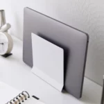 Support pour ordinateur portable Yamazaki TOWER vertical, de couleur blanche, en position inclinée avec un ordinateur portable devant un mur blanc, en gros plan