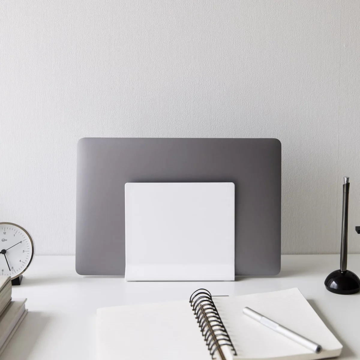 Support pour ordinateur portable Yamazaki TOWER vertical, blanc, vu de face sur le bureau avec un bloc-notes