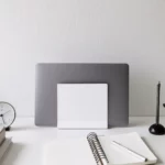 Support pour ordinateur portable Yamazaki TOWER vertical, blanc, vu de face sur le bureau avec un bloc-notes