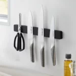 Yamazaki TOWER Magnetic Knife Rack in Black, mounted on the kitchen wall with three knives and a pair of scissors