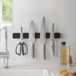 Yamazaki TOWER Magnetic Knife Rack in Black, above the sink with knives next to the oil and pepper shakers