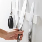 Yamazaki TOWER Magnetic Knife Rack in White; a hand picks up a knife from the rack