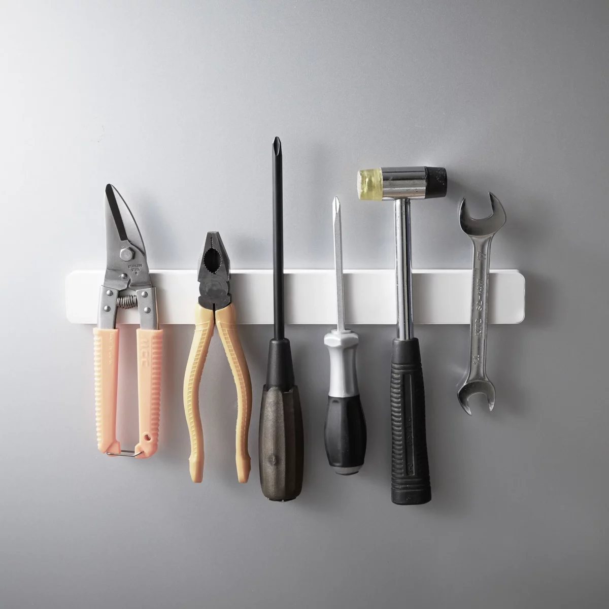 Yamazaki TOWER Magnetic Knife Rack in White, with pliers, screwdriver, and hammer on a gray wall