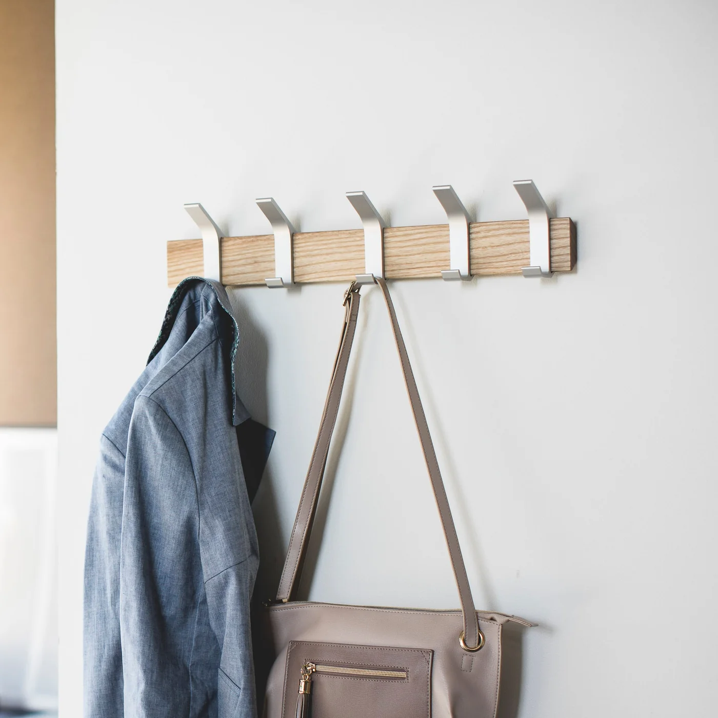 Yamazaki RIN Wandgarderobe aus Holz mit verschiebbaren Metallhaken, daran Jacke und Tasche