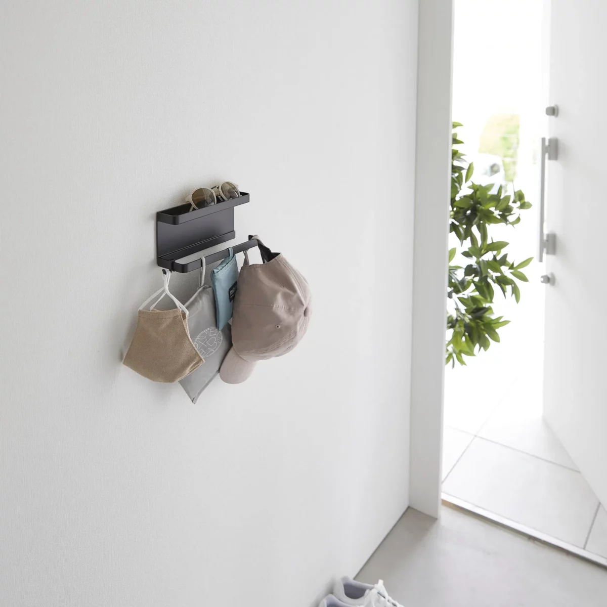 Yamazaki Schirmhalter SMART für die Wand in Schwarz, mit Mützen und Masken an der Stange