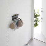 Yamazaki Schirmhalter SMART für die Wand in Schwarz, mit Mützen und Masken an der Stange