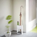 Yamazaki narrow oval umbrella stand in white, in the bright entryway next to a plant with a parasol
