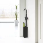 Porte-parapluies Yamazaki SMART d'angle, noir, avec un parapluie droit et un parapluie pliant vert devant la fenêtre