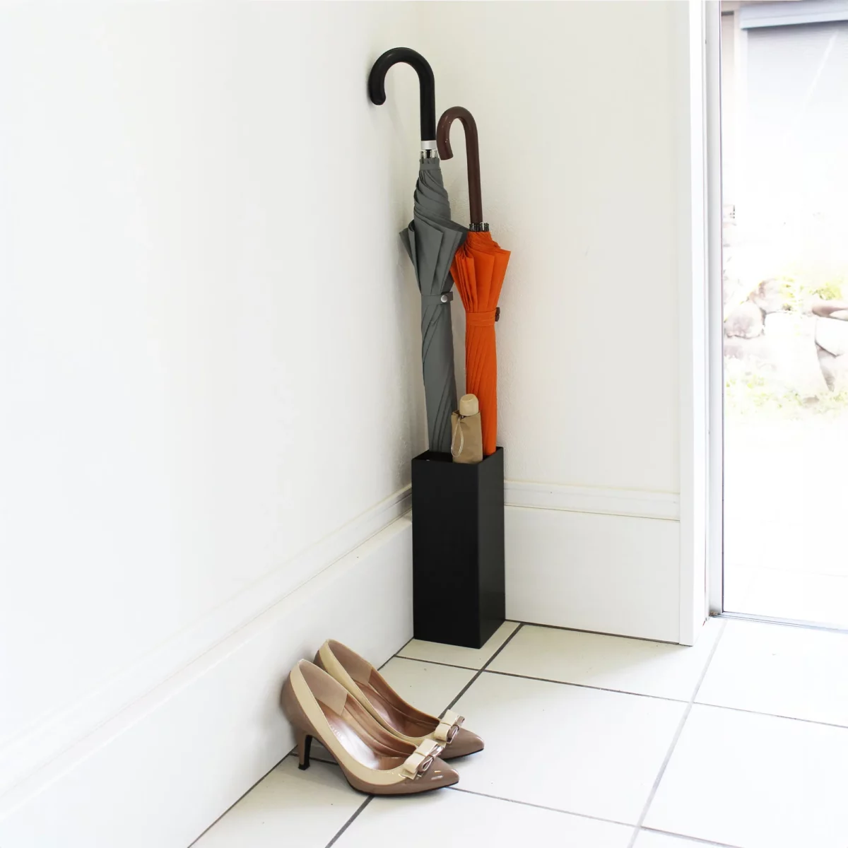 Porte-parapluies Yamazaki SMART d'angle, noir, placé dans le coin près de la porte, avec des parapluies et des chaussures