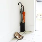 Porte-parapluies Yamazaki SMART d'angle, noir, placé dans le coin près de la porte, avec des parapluies et des chaussures