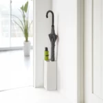 Porte-parapluies Yamazaki SMART d'angle, blanc, avec un parapluie droit et un parapluie pliant vert devant la fenêtre