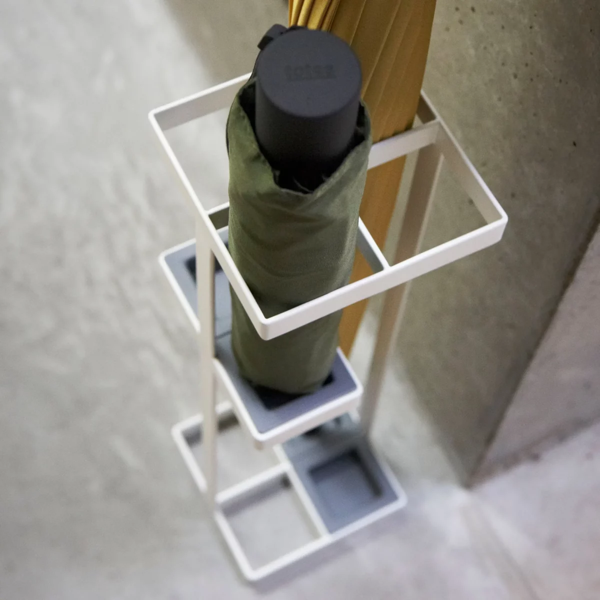 Yamazaki TOWER Slim Umbrella Stand in White, shown from above with a folding umbrella in the top compartment