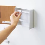 Yamazaki RIN Magnetic Key Box in White; a hand moves a hook along the rail