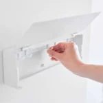Yamazaki TOWER Wide Key Cabinet in White; a hand moves one of the eight hooks on the inner rail