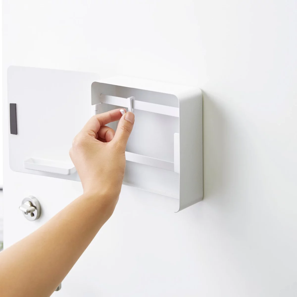 Yamazaki Schlüsselkasten TOWER magnetisch in Weiss, Hand versetzt einen Haken im geöffneten Kasten