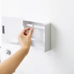 Yamazaki Schlüsselkasten TOWER magnetisch in Weiss, Hand versetzt einen Haken im geöffneten Kasten