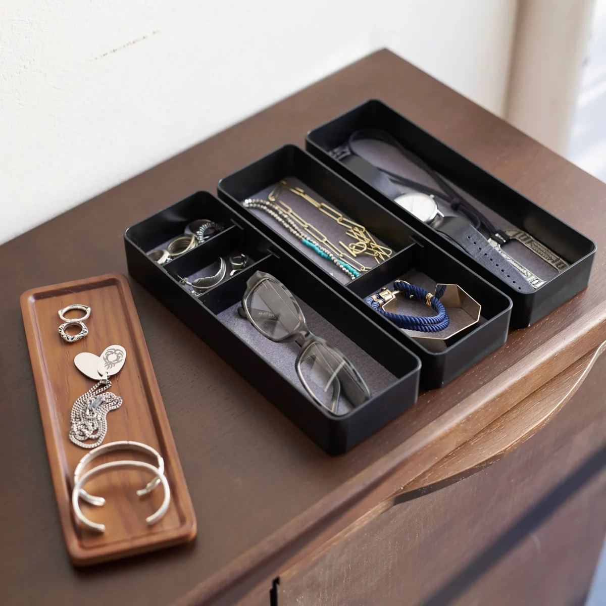 Yamazaki RIN 3-Tier Slim Jewelry Box in Black, with compartments lined with glasses, pearls, and earrings